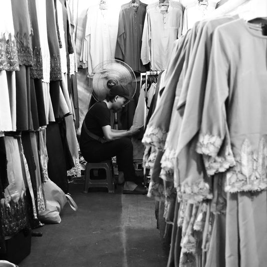 Person working in a crowded clothing shop aisle